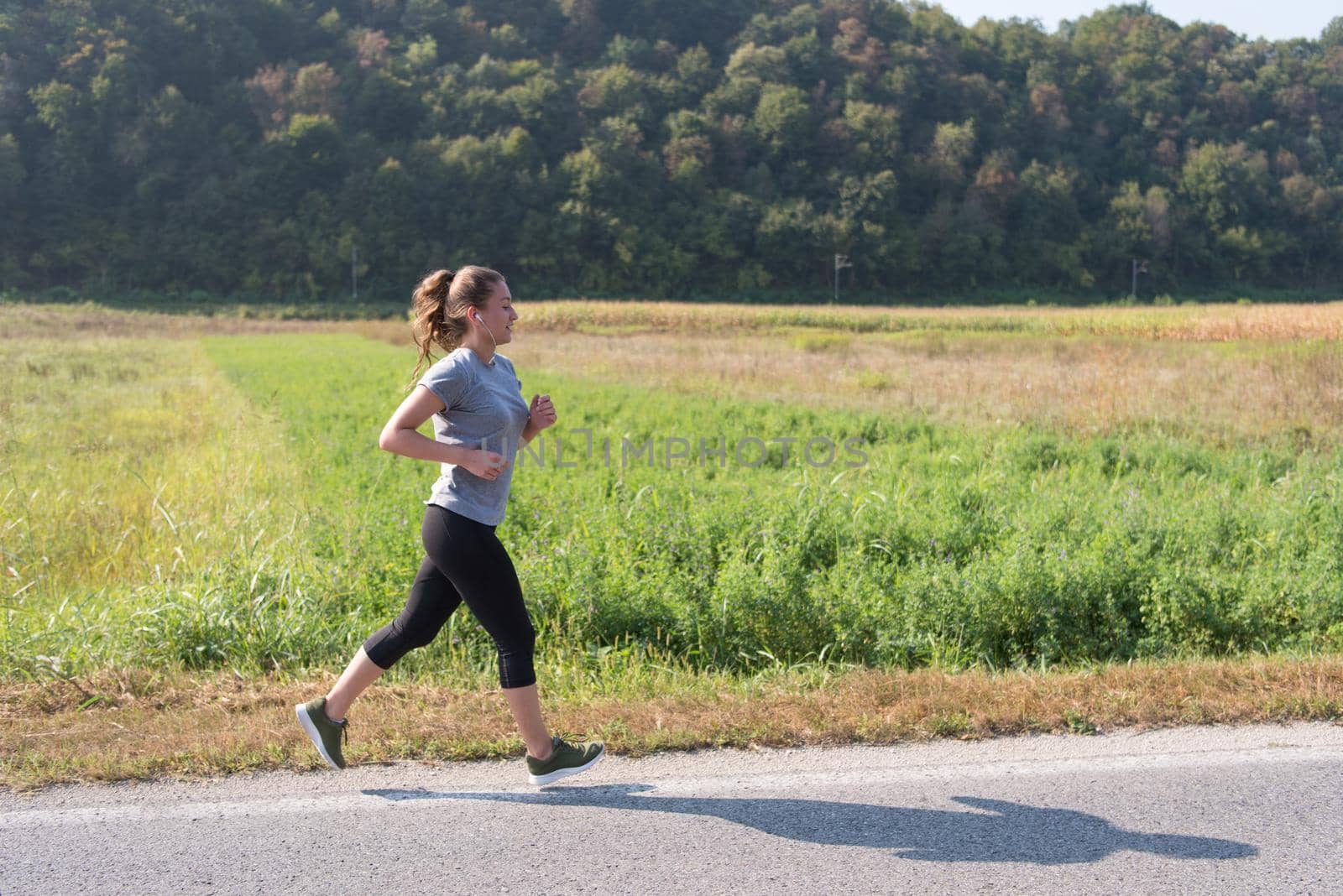 young woman enjoying in a healthy lifestyle while jogging along a country road, exercise and fitness concept