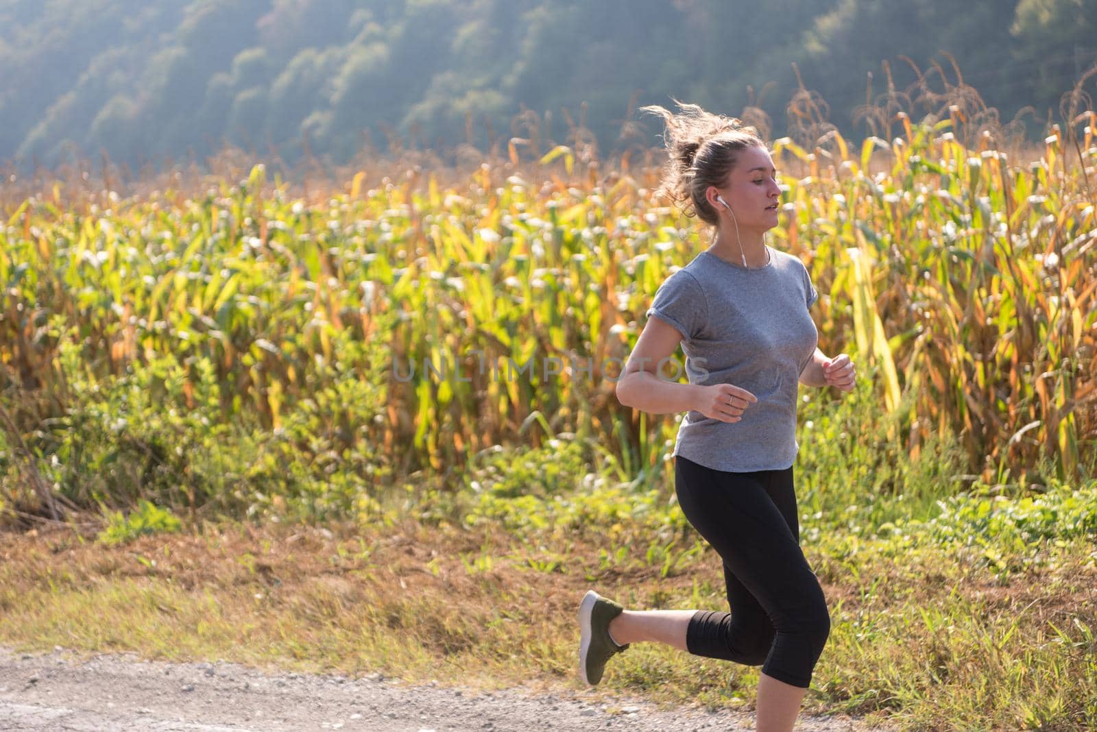 young woman enjoying in a healthy lifestyle while jogging along a country road, exercise and fitness concept