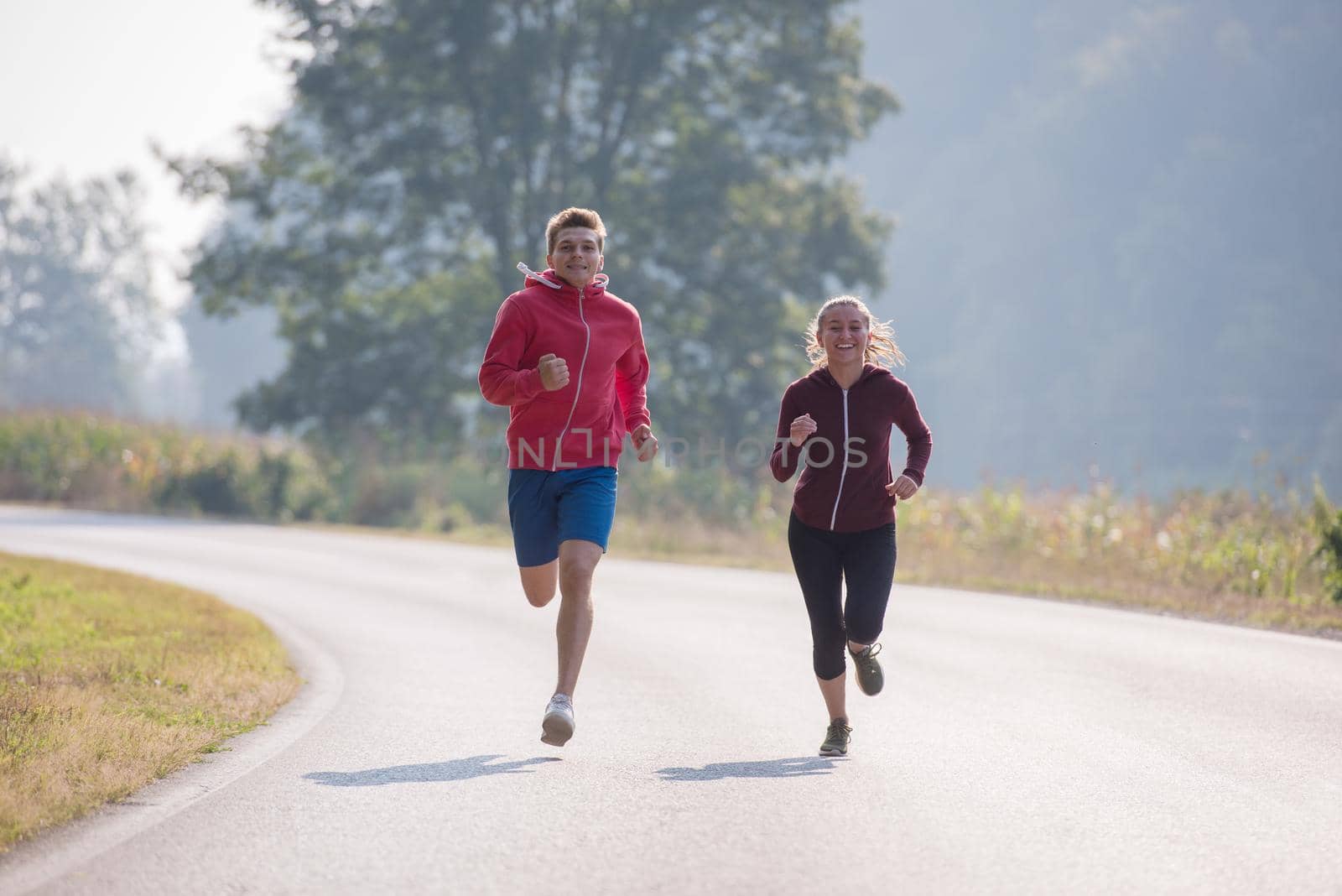 young couple jogging along a country road by dotshock