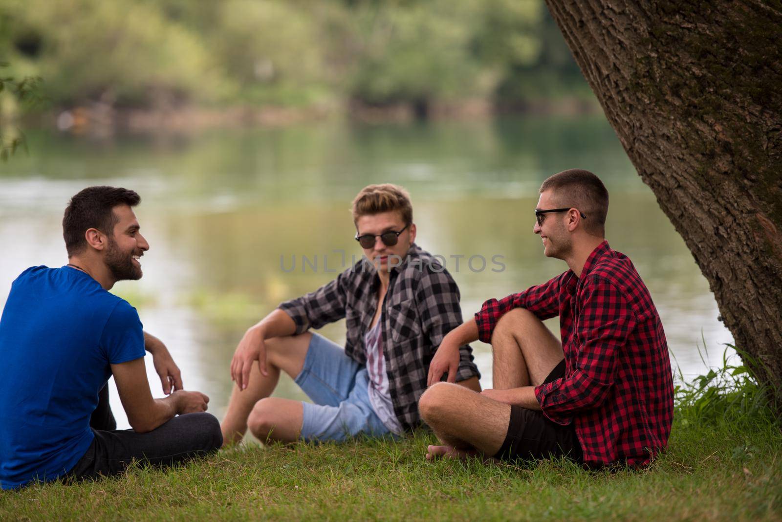 Group of young  men enjoying the nature sitting on the bank of the river