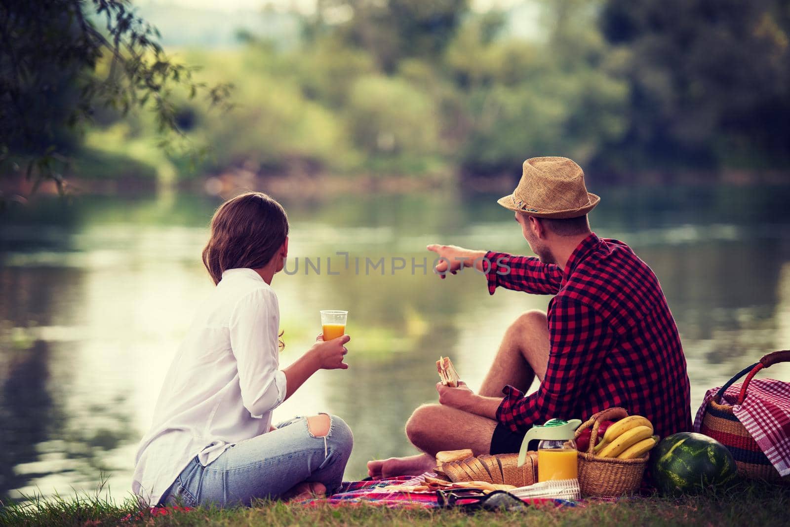 Couple in love enjoying picnic time drink and food in beautiful nature on the river bank