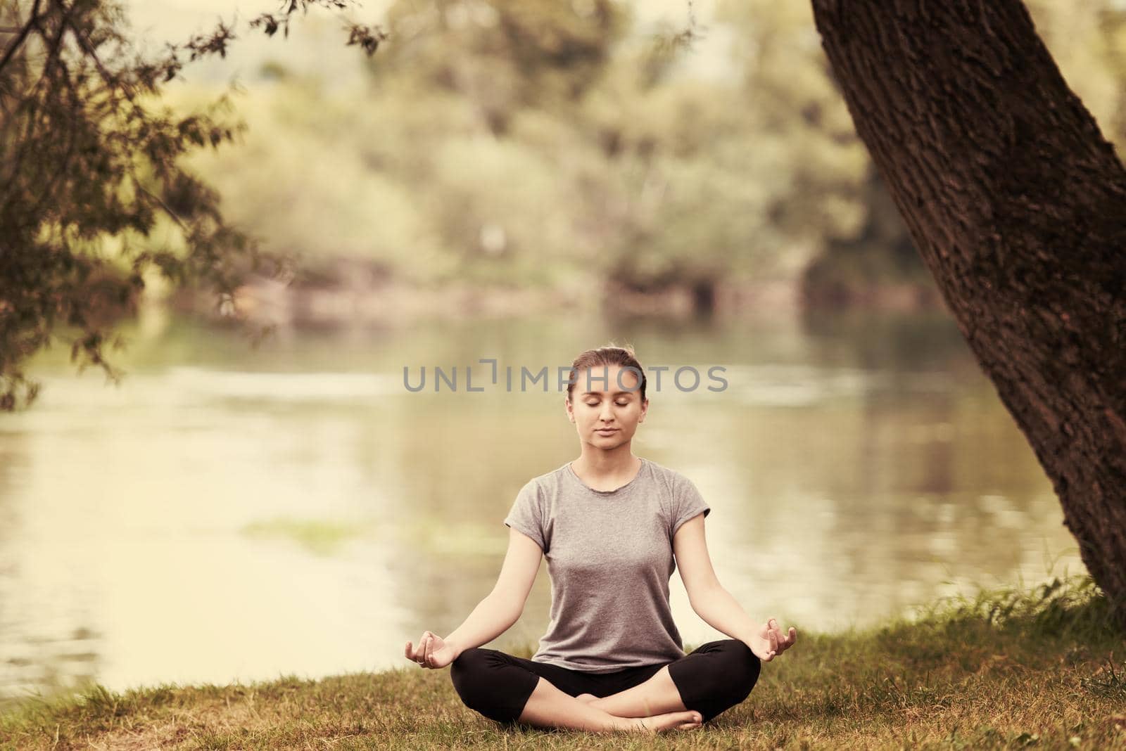 healthy woman relaxing while meditating and doing yoga exercise in the beautiful nature on the bank of the river