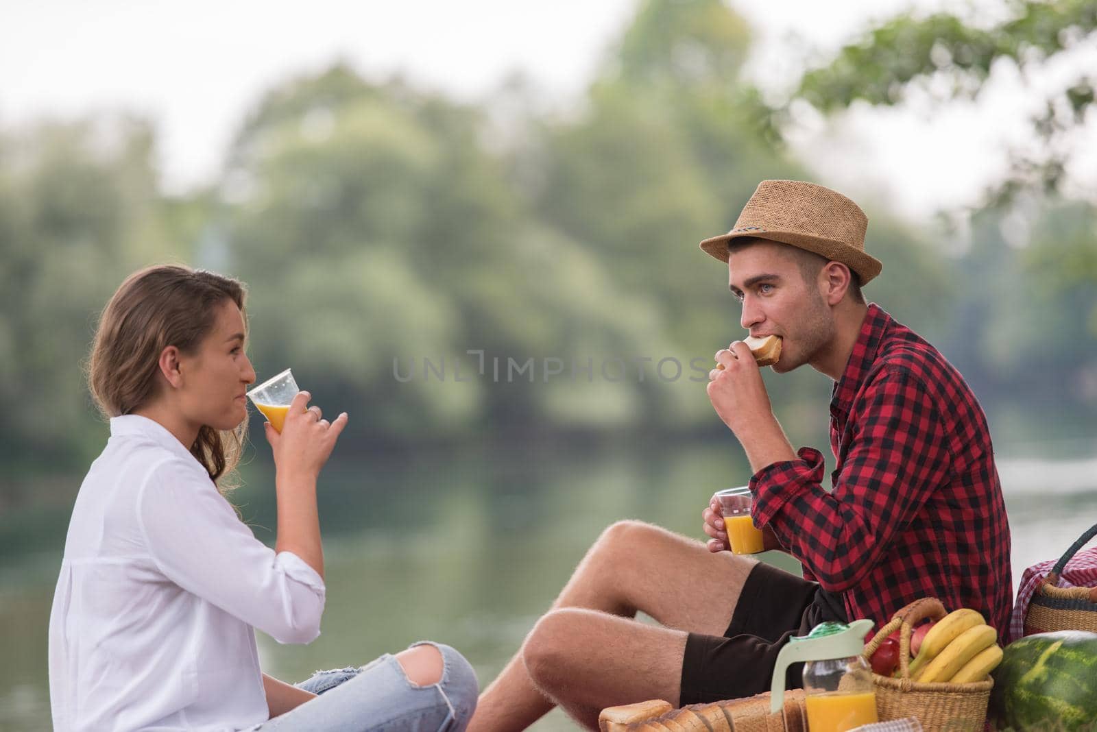 Couple in love enjoying picnic time drink and food in beautiful nature on the river bank