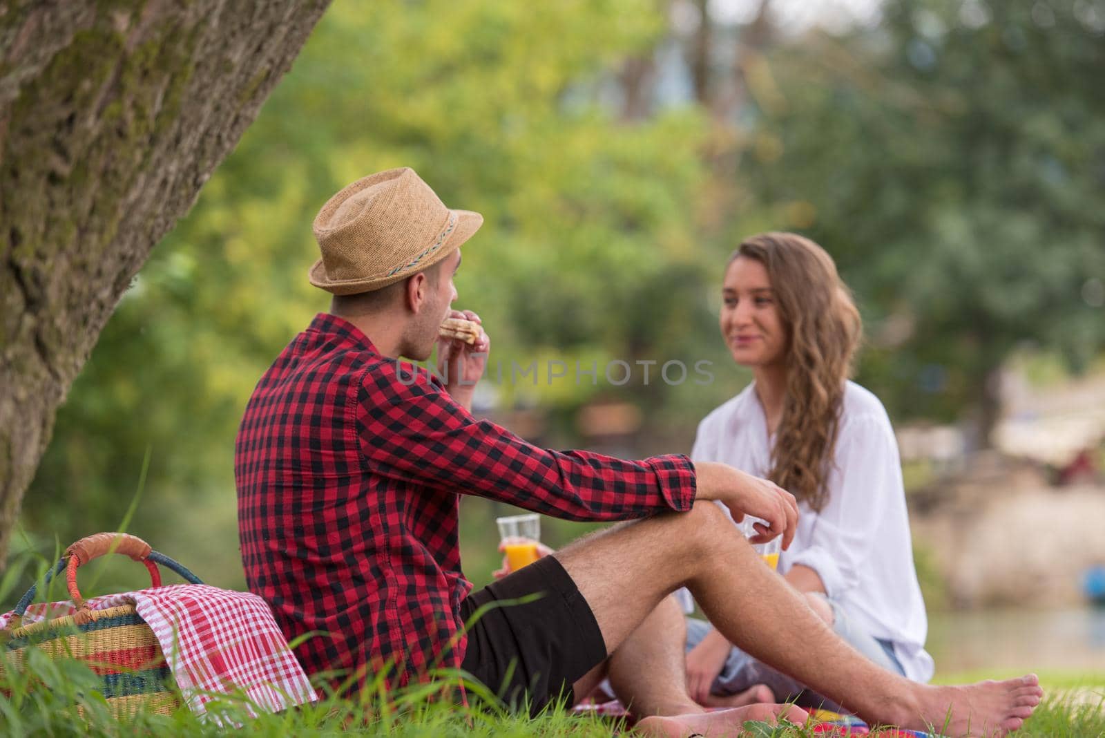 Couple in love enjoying picnic time drink and food in beautiful nature on the river bank