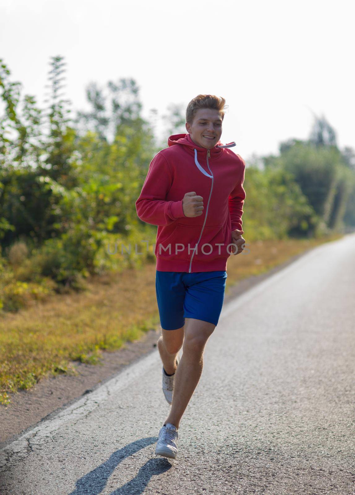 young man enjoying in a healthy lifestyle while jogging along a country road, exercise and fitness concept