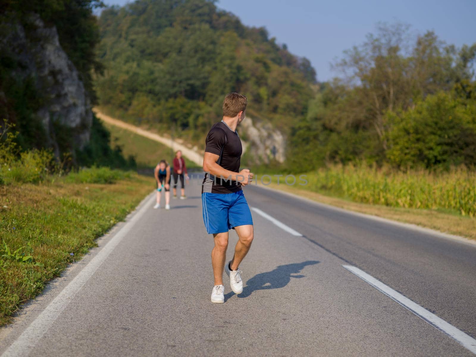 group of young people jogging on country road runners running on open road on a summer day