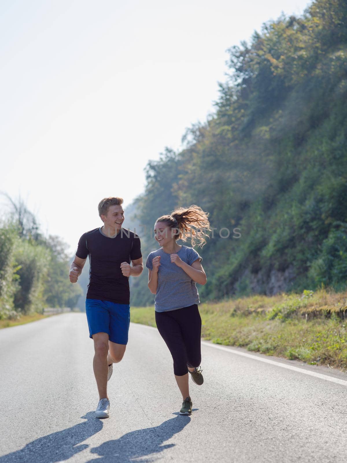 young couple enjoying in a healthy lifestyle while jogging along a country road, exercise and fitness concept