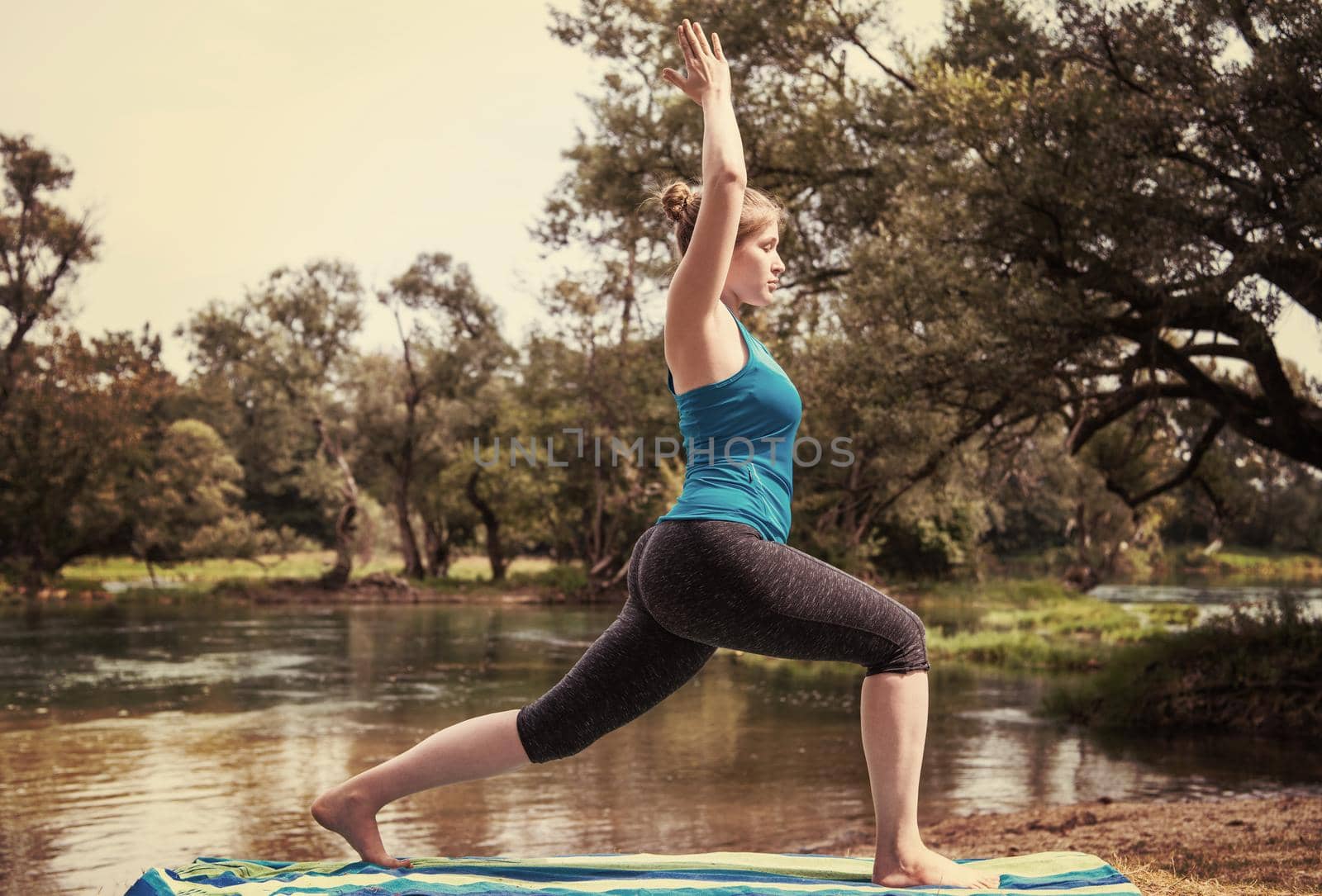 healthy woman relaxing while meditating and doing yoga exercise in the beautiful nature on the bank of the river