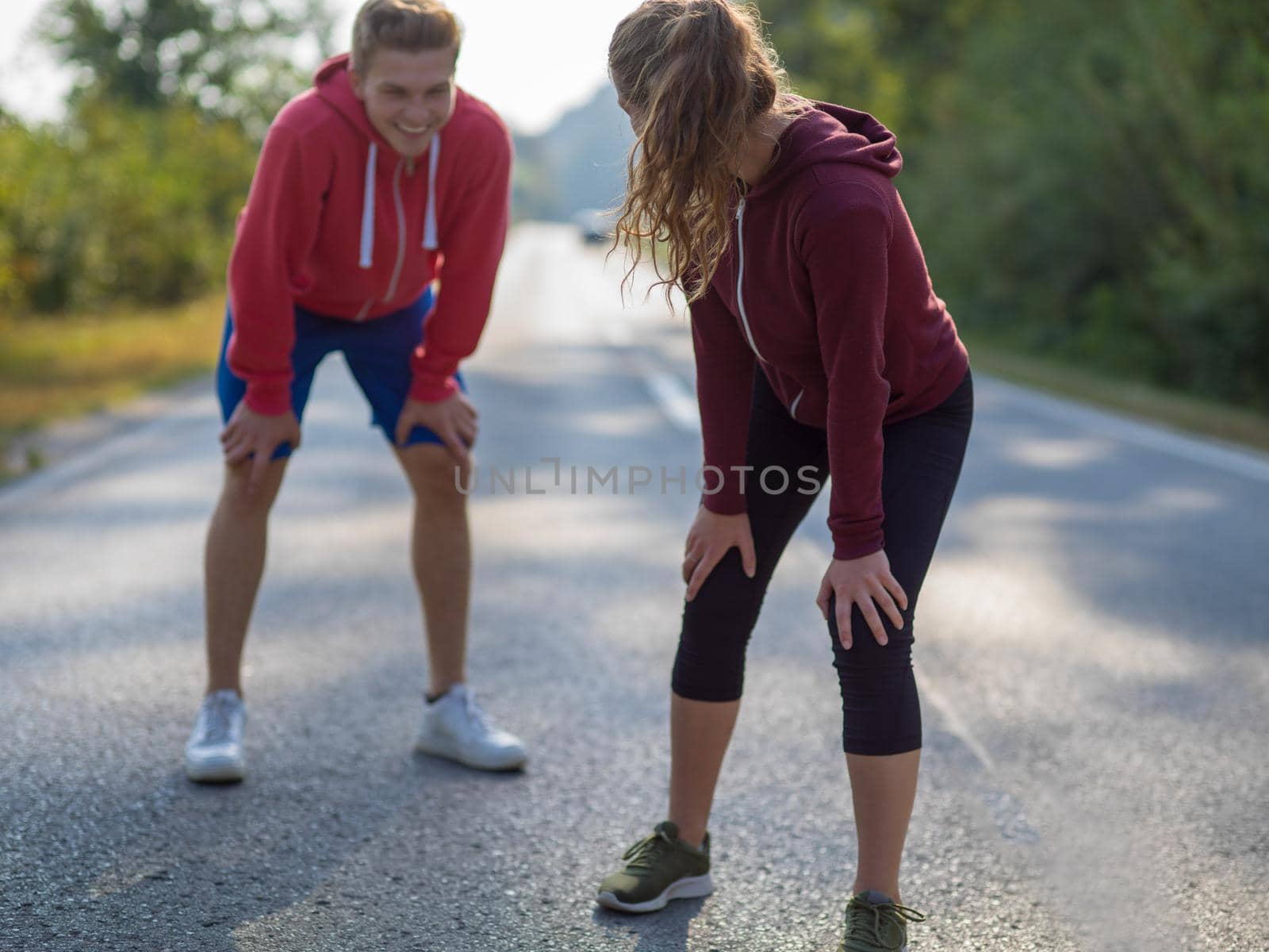 young couple warming up and stretching on a country road by dotshock