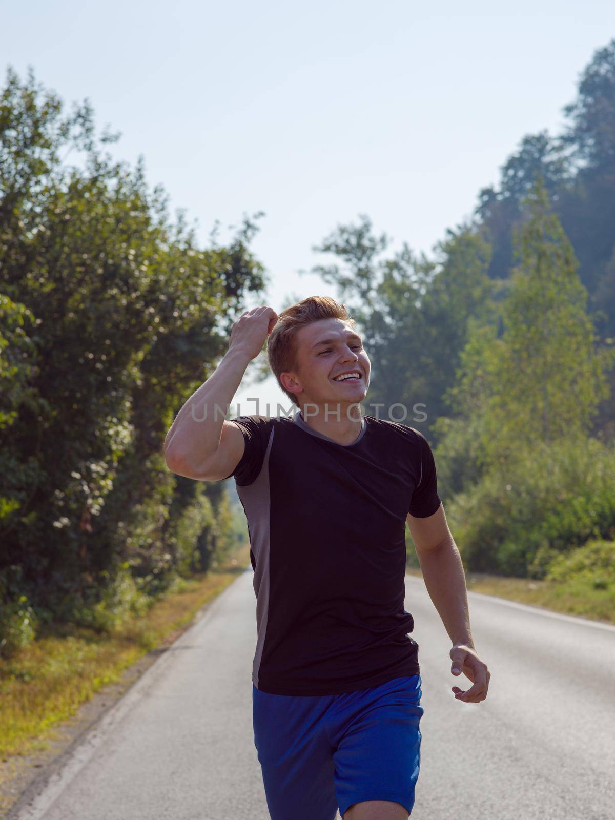 young man enjoying in a healthy lifestyle while jogging along a country road, exercise and fitness concept