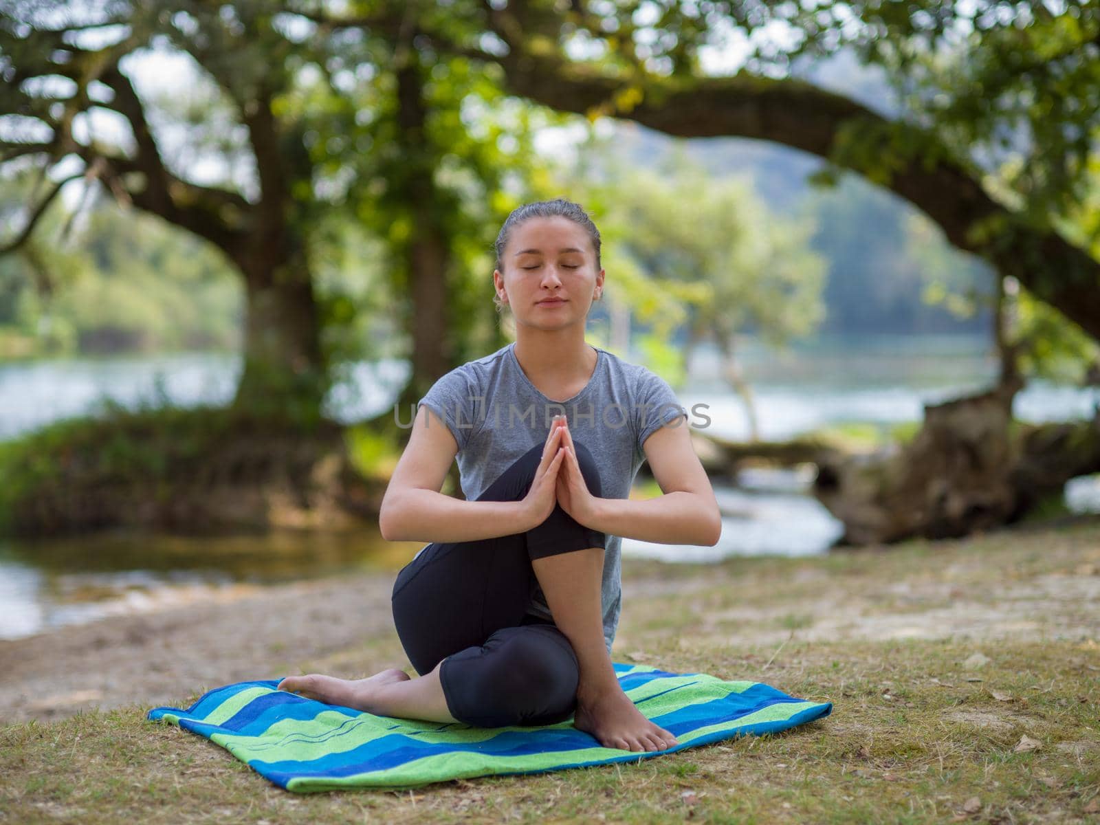 healthy woman relaxing while meditating and doing yoga exercise in the beautiful nature on the bank of the river