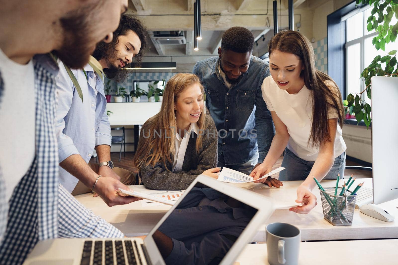 Team of diverse multiracial coworkers in modern office discuss their project together