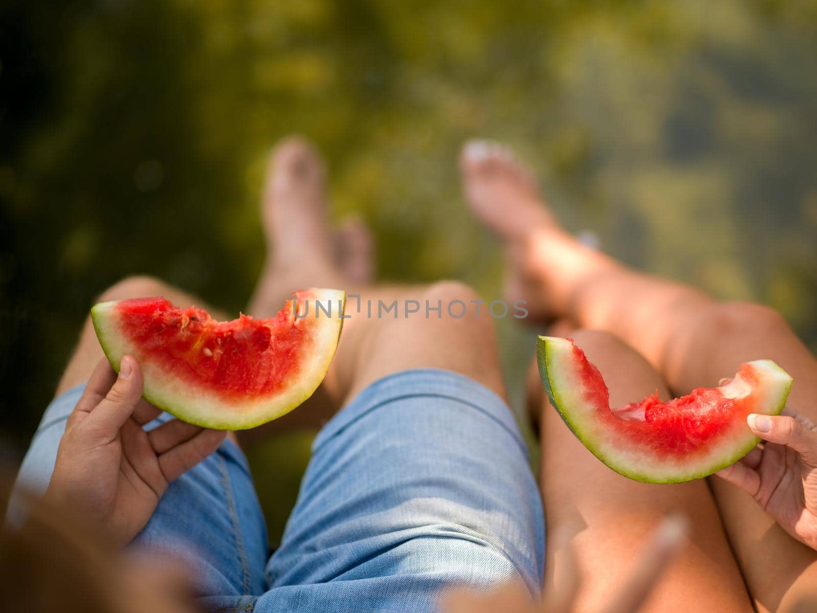 Couple in love enjoying picnic time eating watermelon in beautiful nature on the river bank