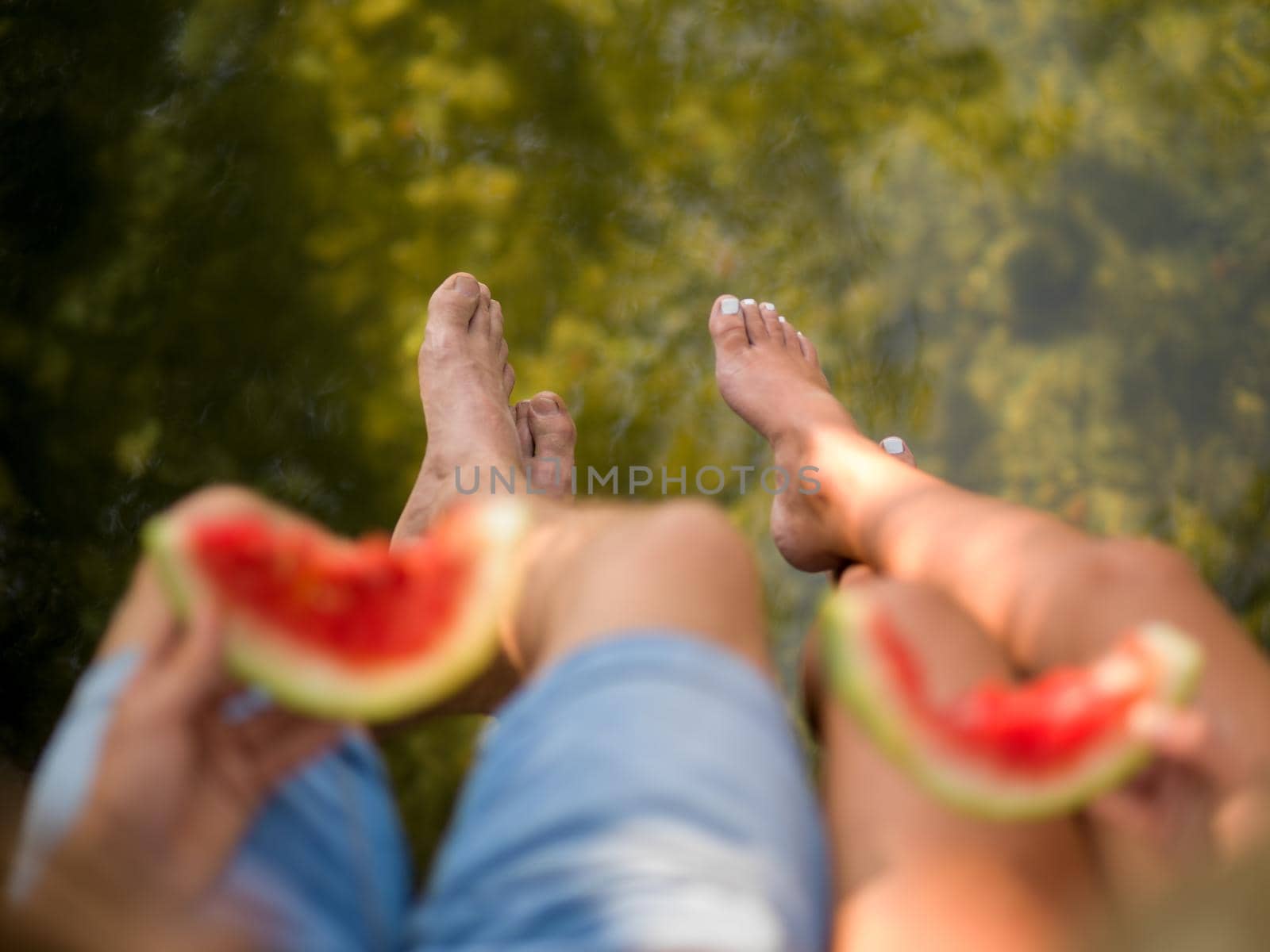 Couple in love enjoying picnic time eating watermelon in beautiful nature on the river bank