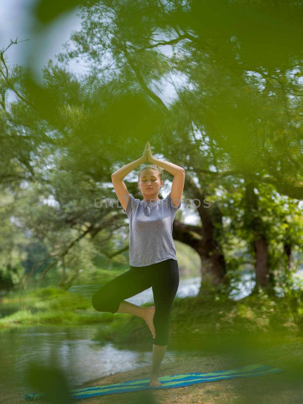 healthy woman relaxing while meditating and doing yoga exercise in the beautiful nature on the bank of the river