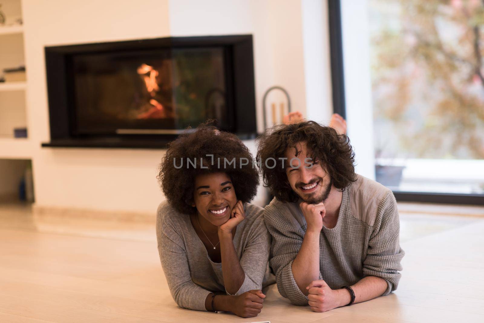 multiethnic couple lying on the floor  in front of fireplace by dotshock