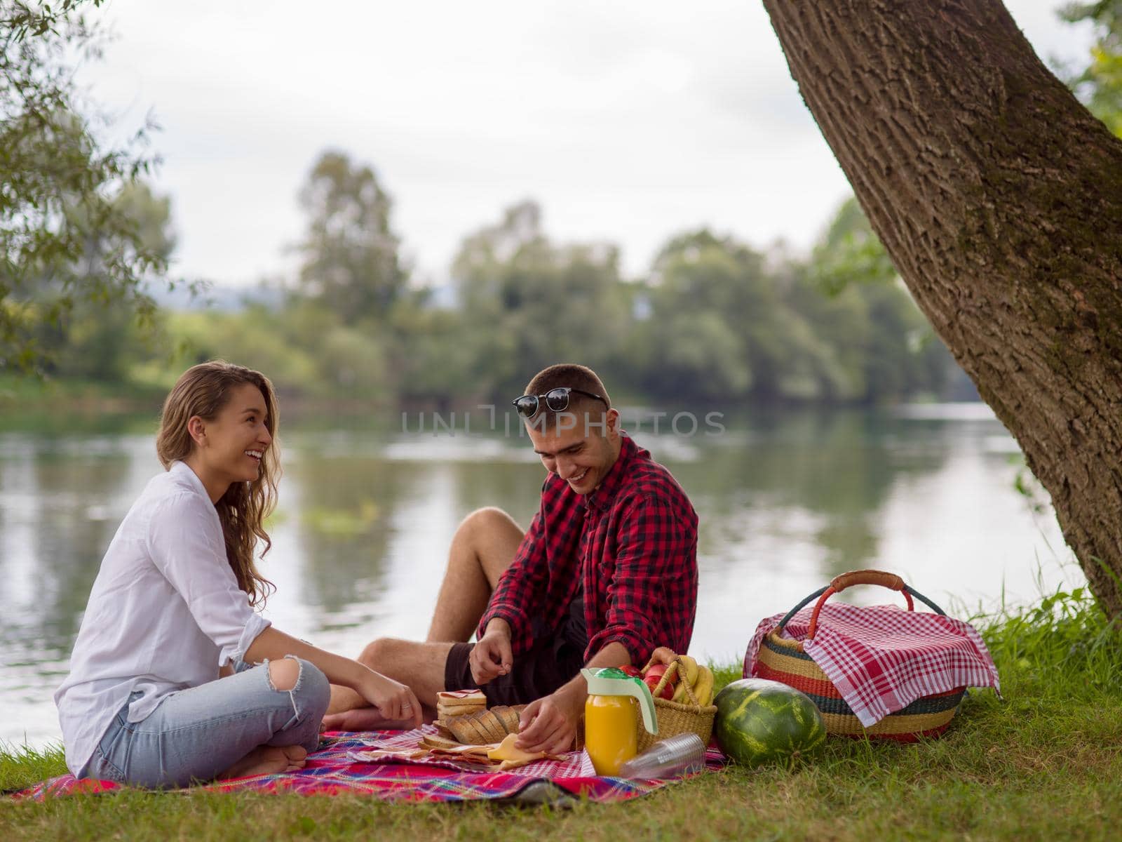 Couple in love enjoying picnic time drink and food in beautiful nature on the river bank