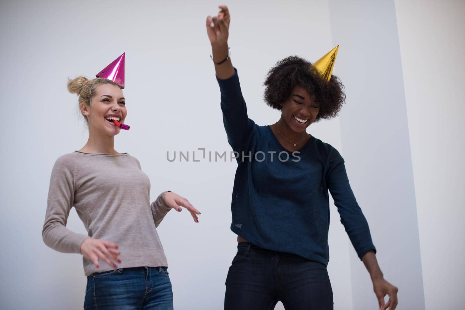 people and celebration concept  young multiethnics smiling women in party caps blowing to whistles