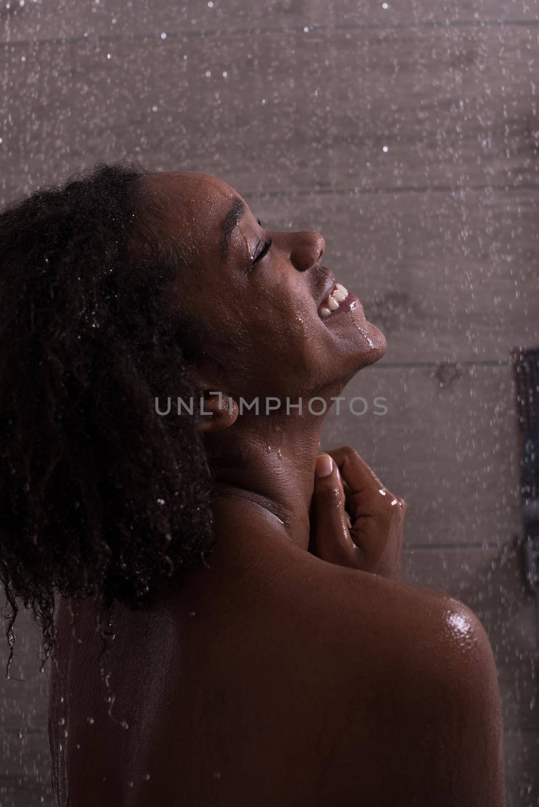 Woman in the shower,beautiful black young female showering under refreshing water, healthy lifestyle, enjoying time in luxury spa resort