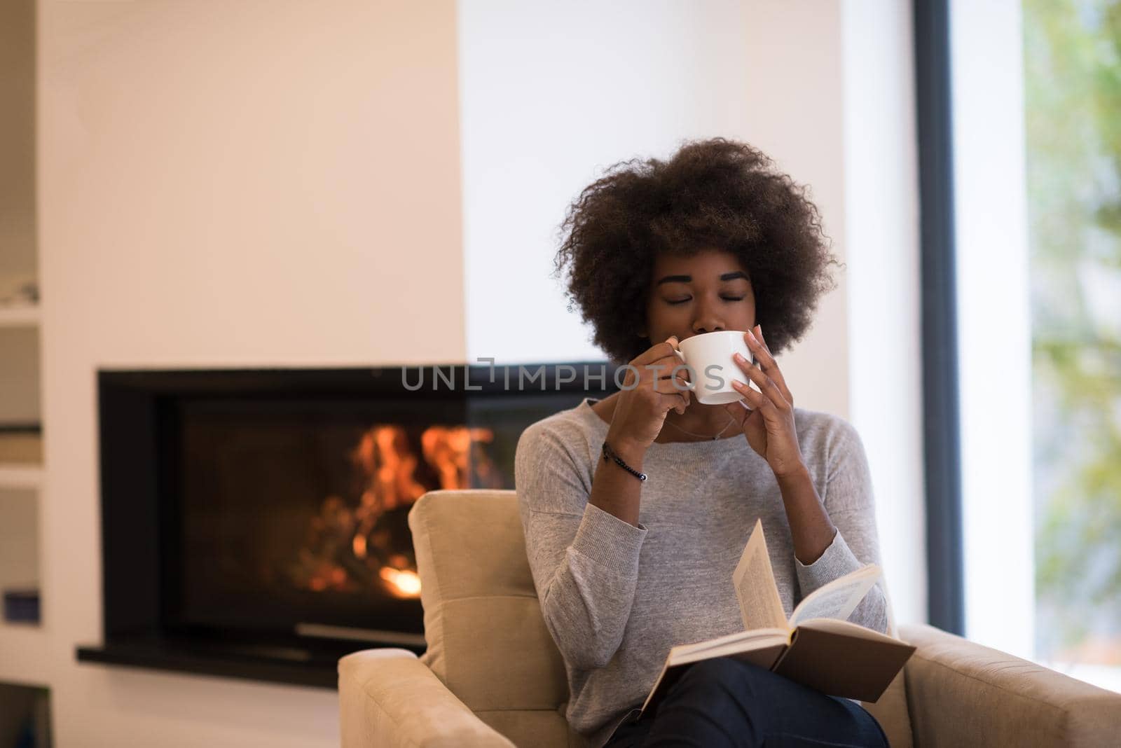 black woman reading book  in front of fireplace by dotshock