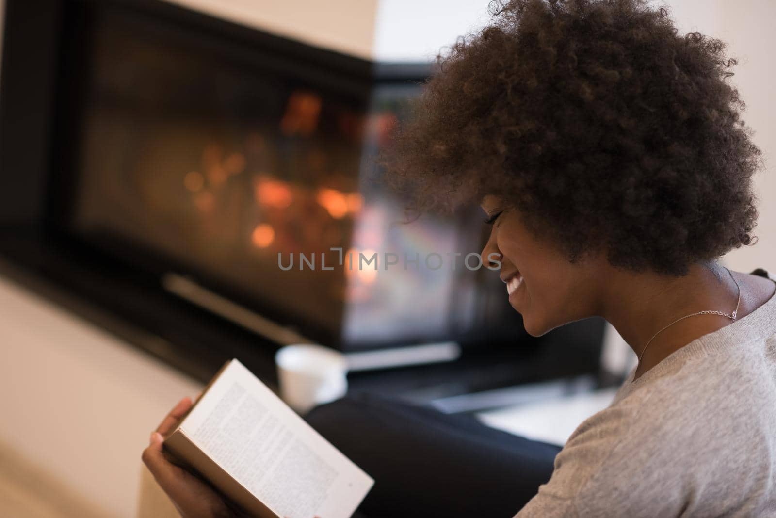 black woman reading book  in front of fireplace by dotshock