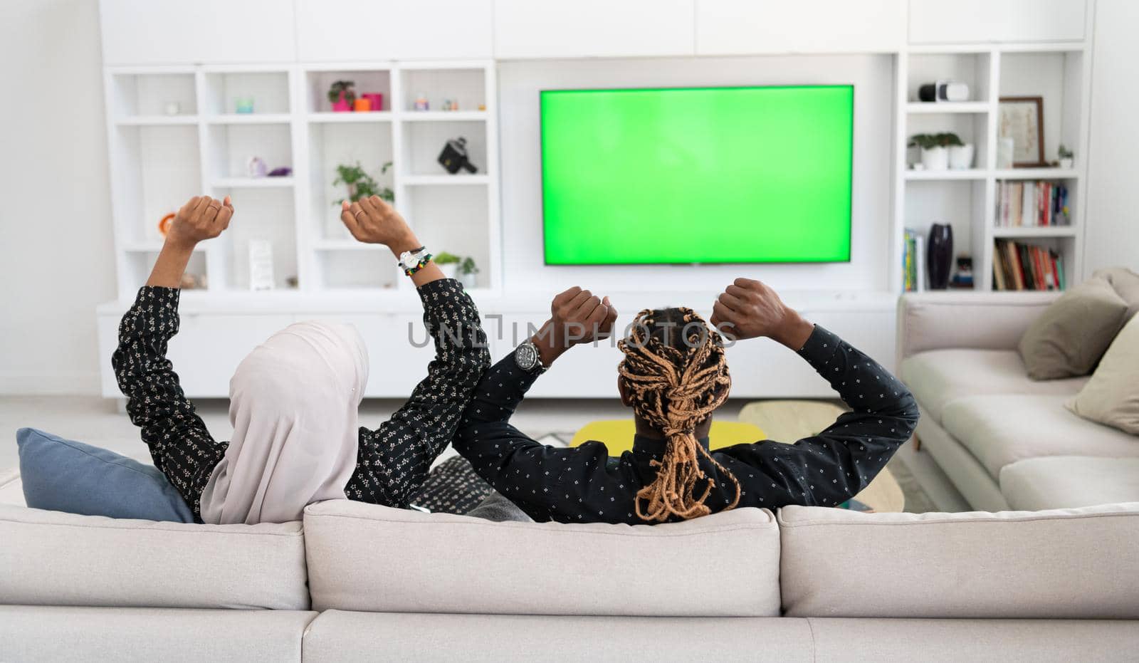 African Couple Sitting On Sofa Watching TV Together Chroma Green Screen Woman Wearing Islamic Hijab Clothes