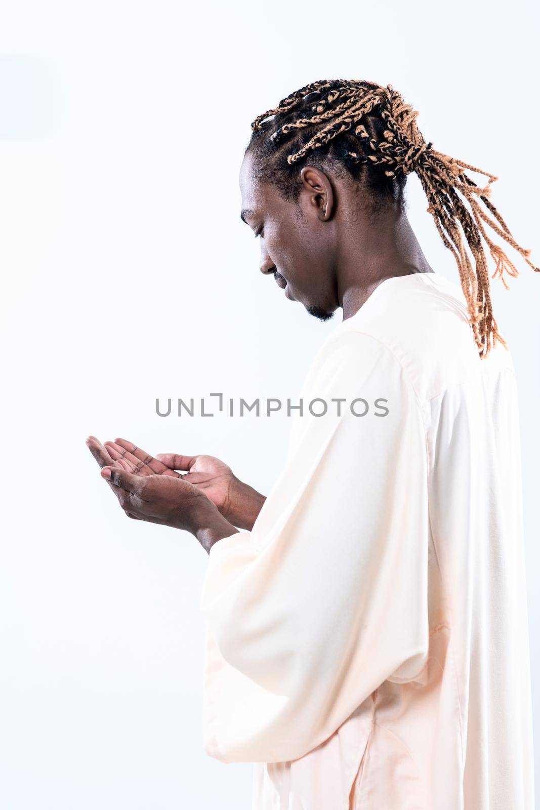 Handsome Young  African Muslim Man Making Traditional Fatiha Prayer To Allah God While Wearing A Traditional Sudan fashion clothes in studio