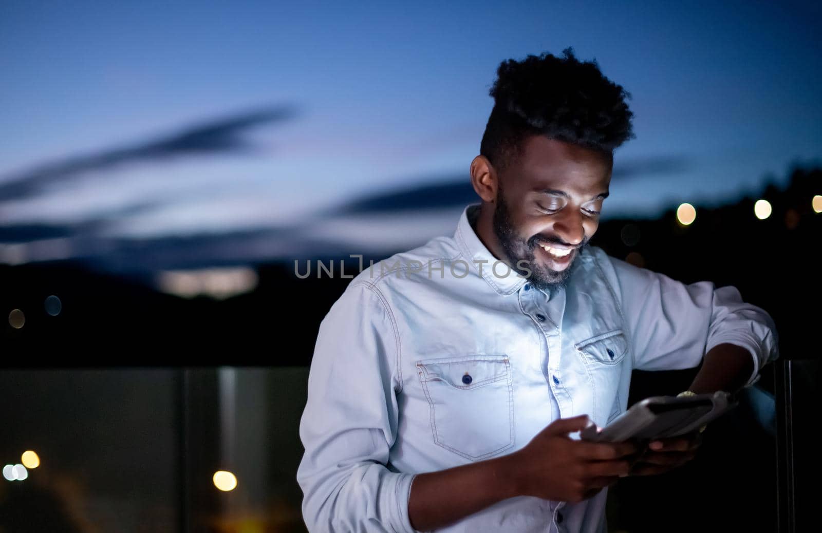 Young  Afro man on street at night using tablet computer by dotshock