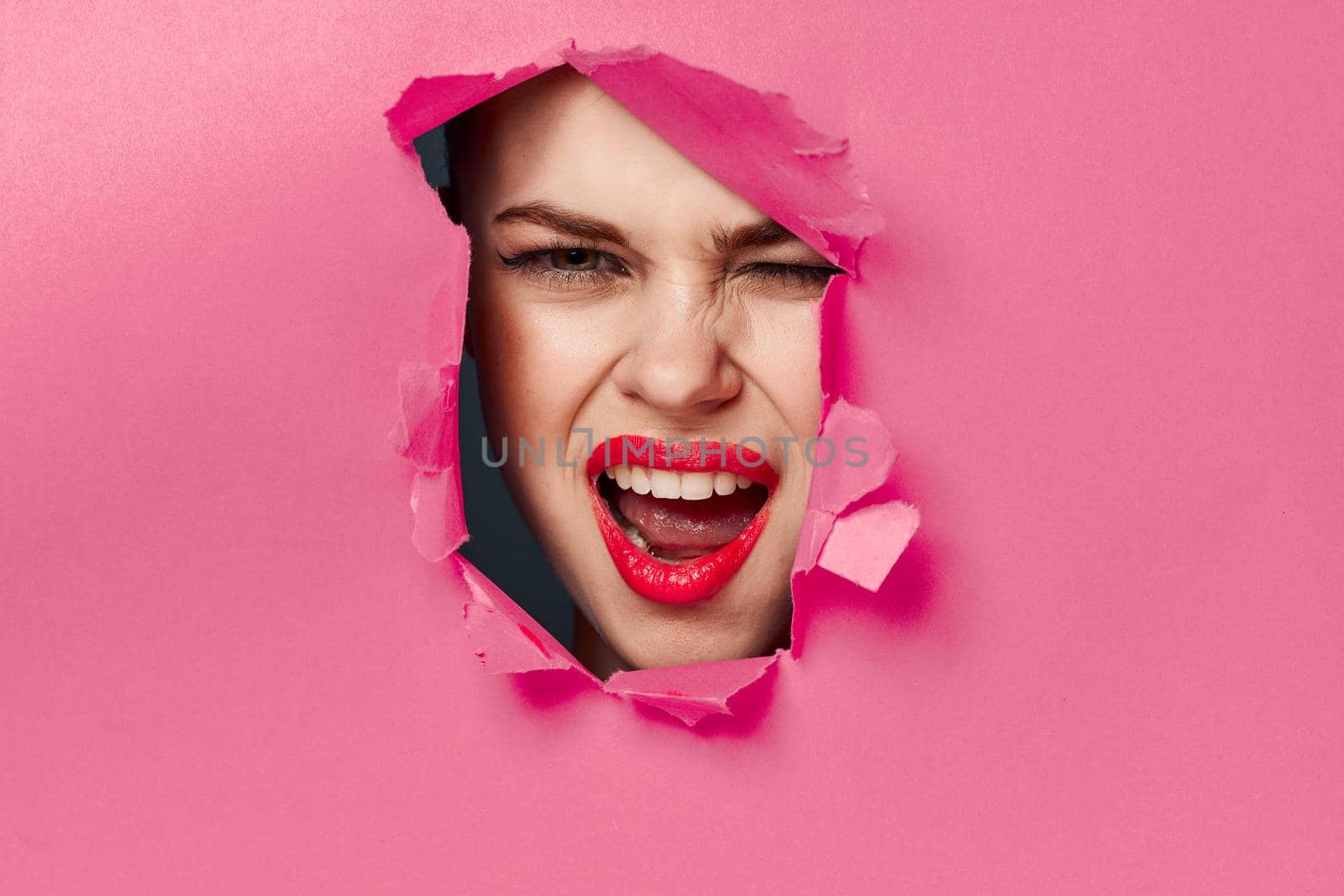 cheerful woman poster hole pink background and red lips. High quality photo