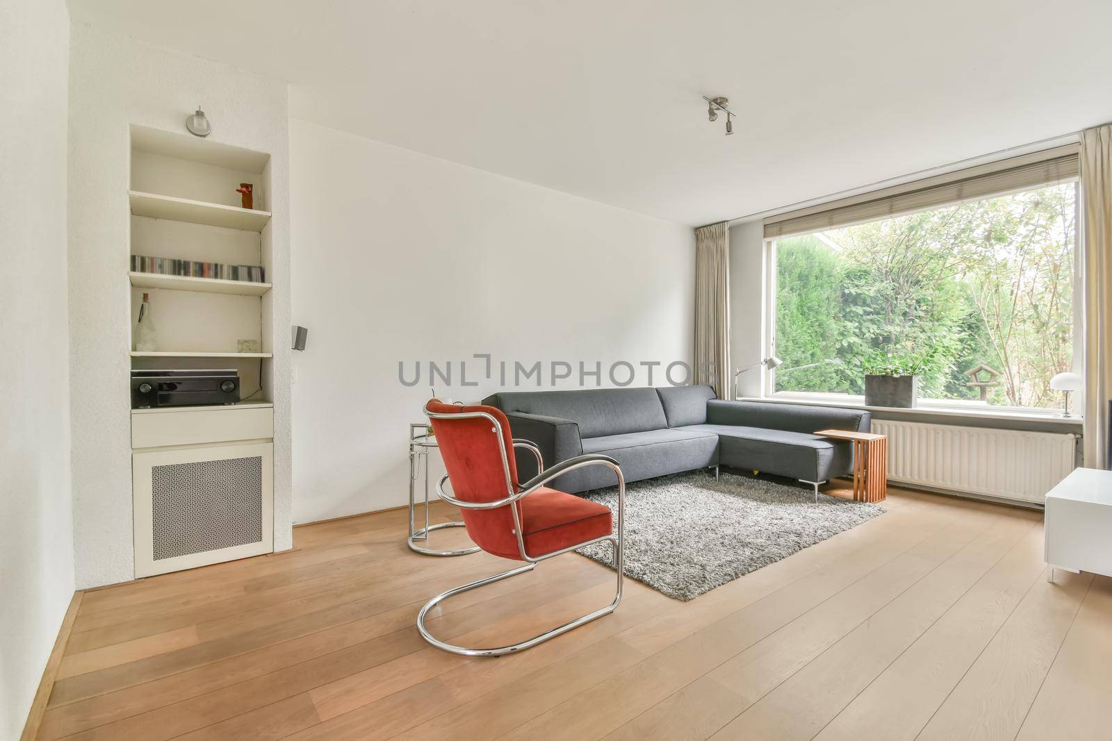 Stylish living room with corner gray sofa and bright red armchair