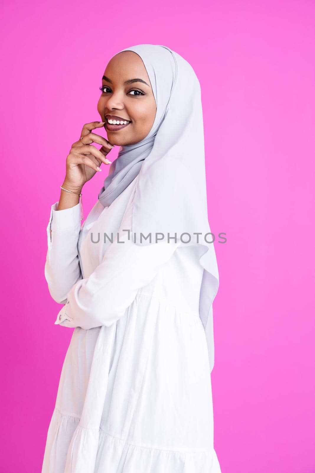 portrait of young modern muslim afro beauty wearing traditional islamic clothes on plastic pink background