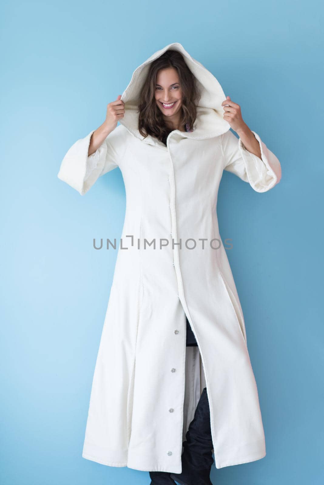 portrait of Beautiful young woman wearing a white coat with hood isolated on blue background