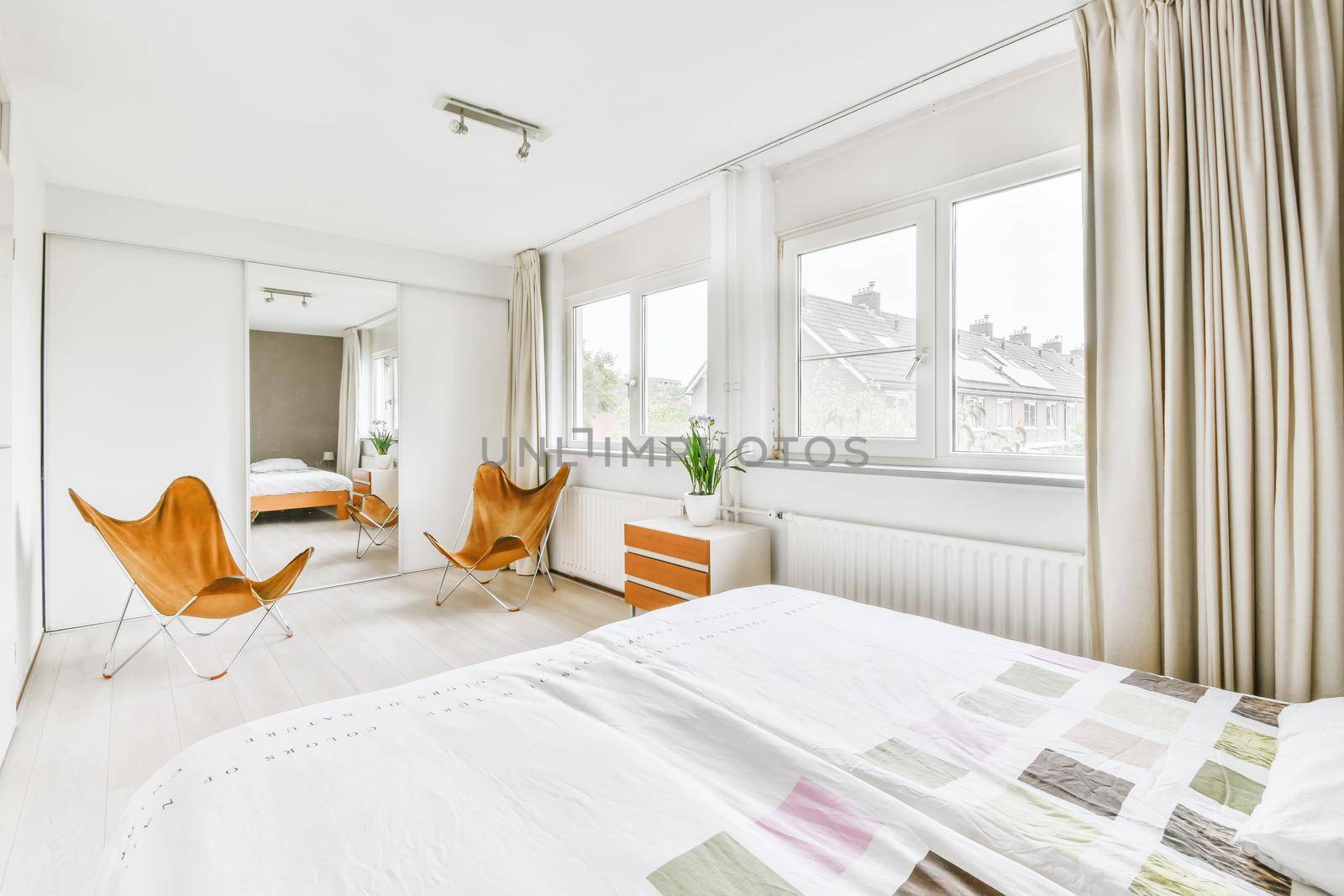 Double bed with soft mattress in a luxurious bedroom with unusual brown chairs