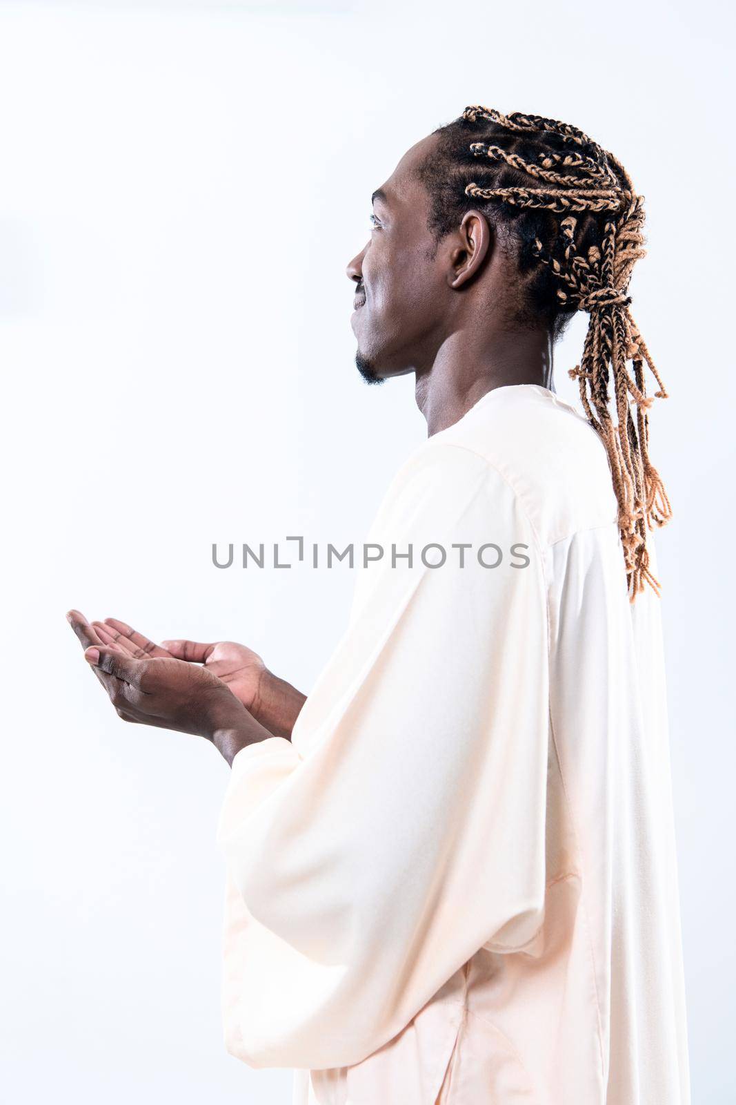 Handsome Young  African Muslim Man Making Traditional Fatiha Prayer To Allah God While Wearing A Traditional Sudan fashion clothes in studio