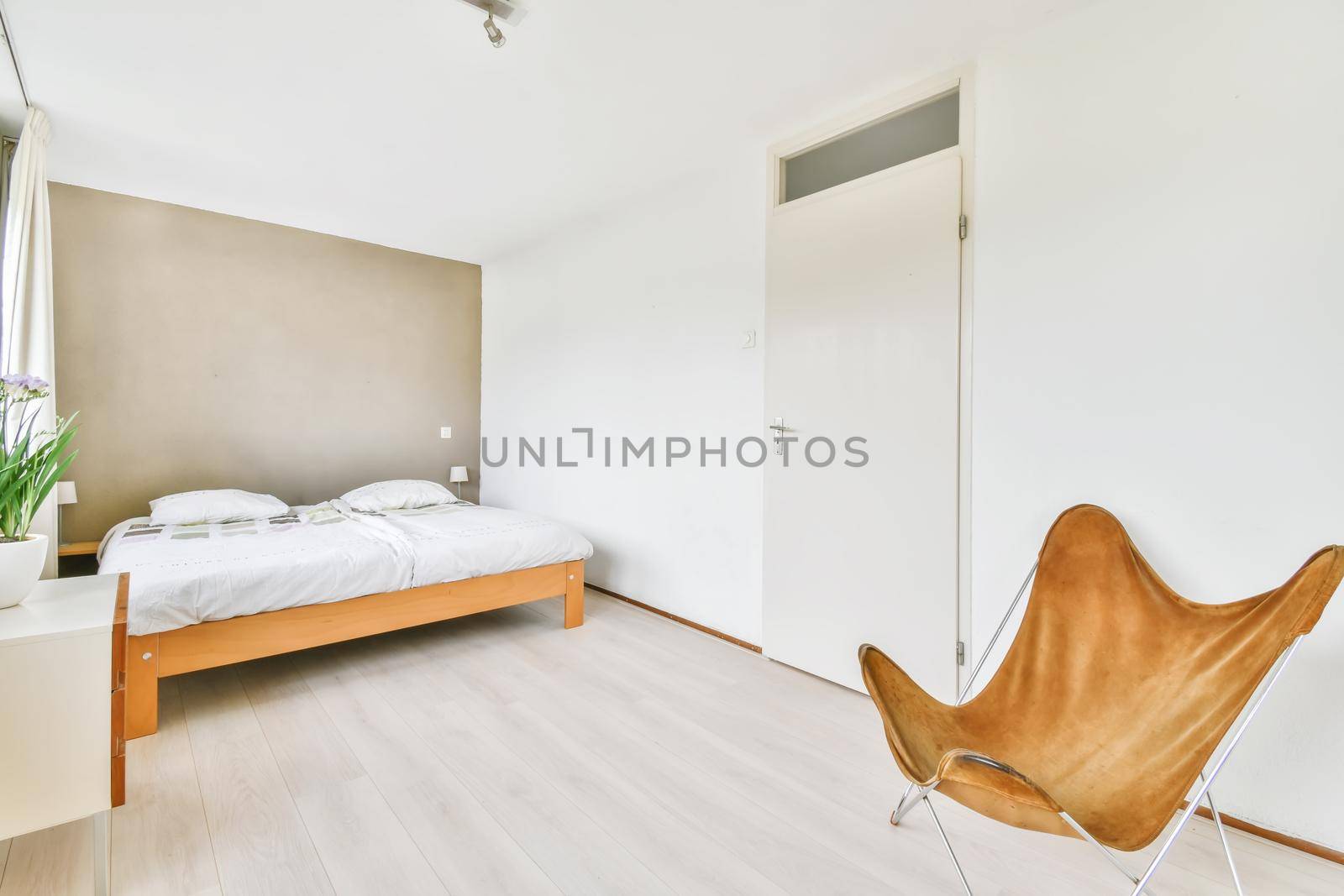 Double bed with soft mattress in a luxurious bedroom with unusual brown chairs