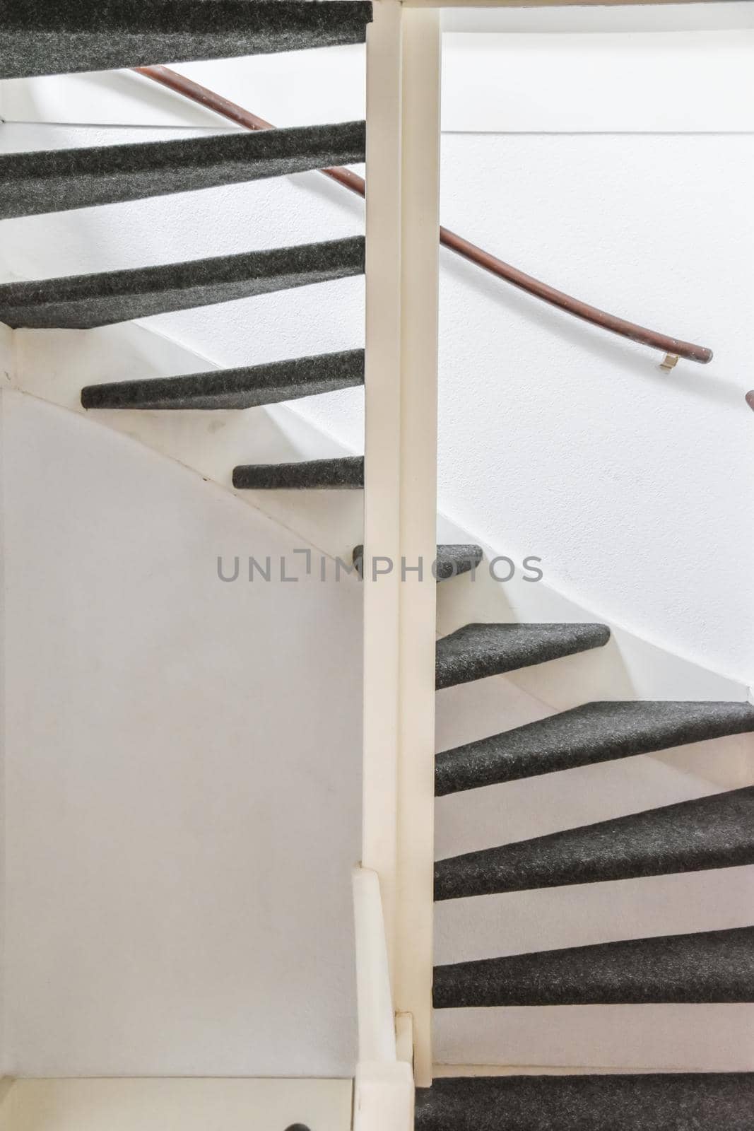 Stylish spiral staircase with black carpet floor and comfortable wooden handrails
