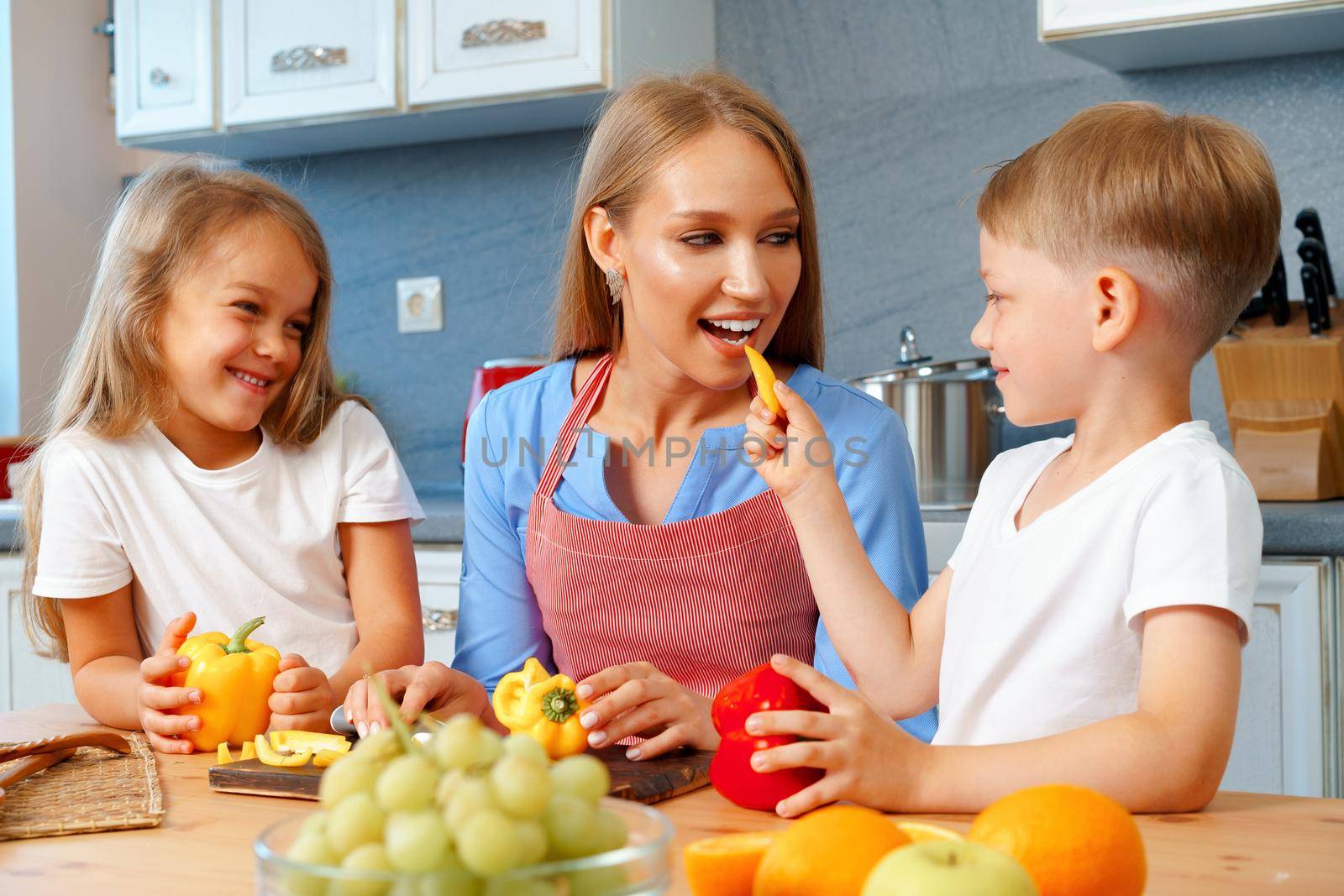 Young mother cooking with her children in kitchen