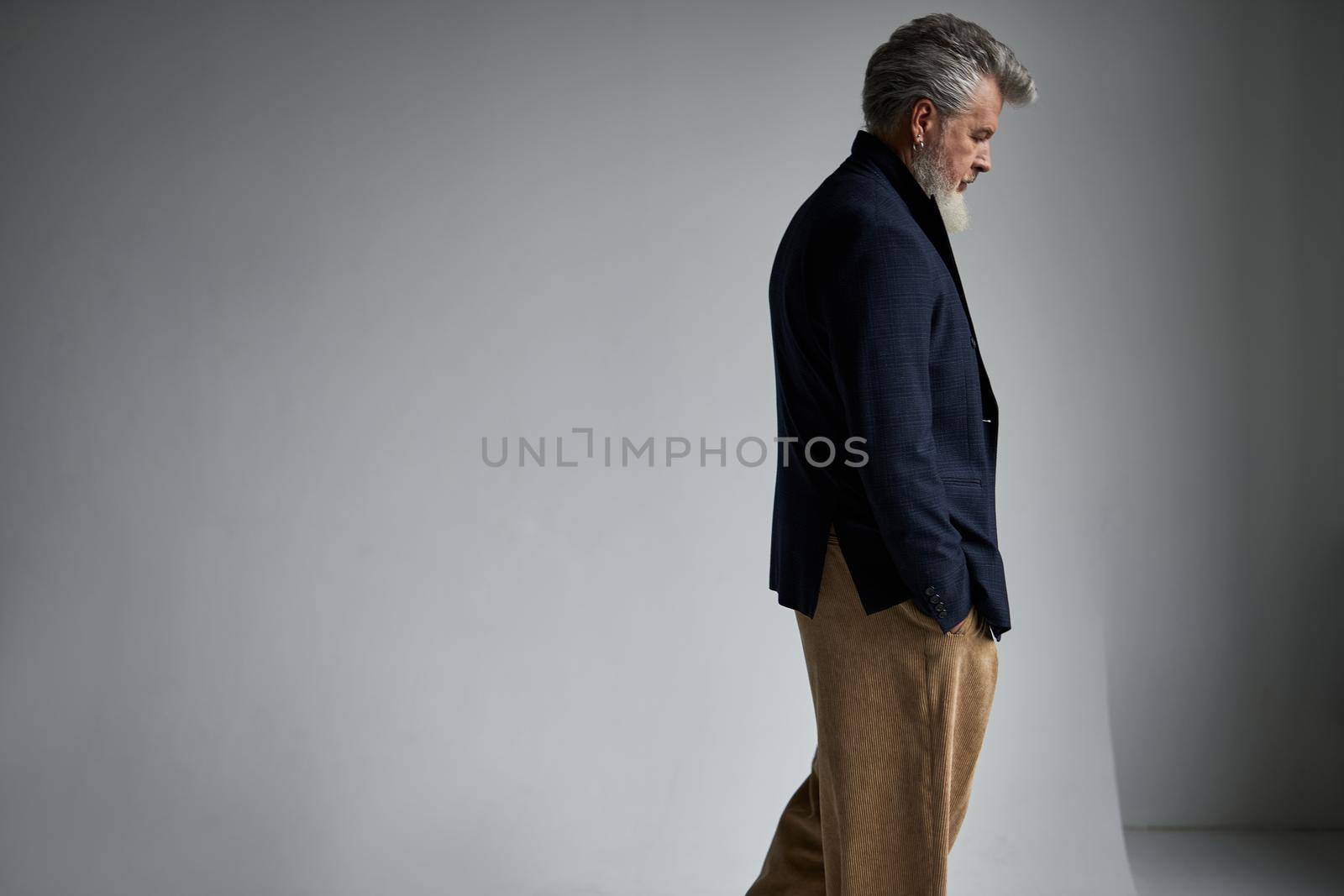 Serious stylish middle aged man in business casual wear looking pensive while standing against white background. Lifestyle, people concept