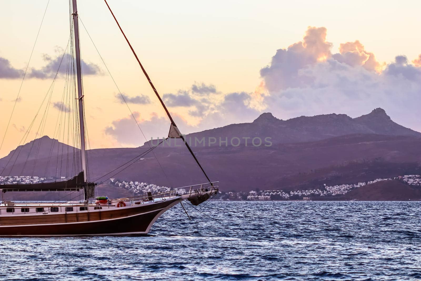 Beautiful sunset on the Aegean Sea with mountains and a sailboat. Seascape, travel and nature concept. High quality photo