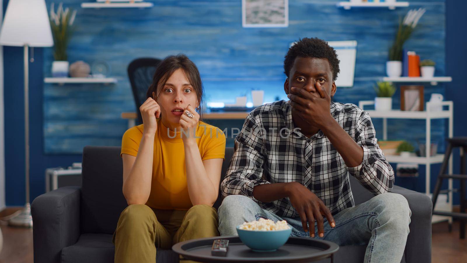 Interracial couple watching drama movie on television by DCStudio