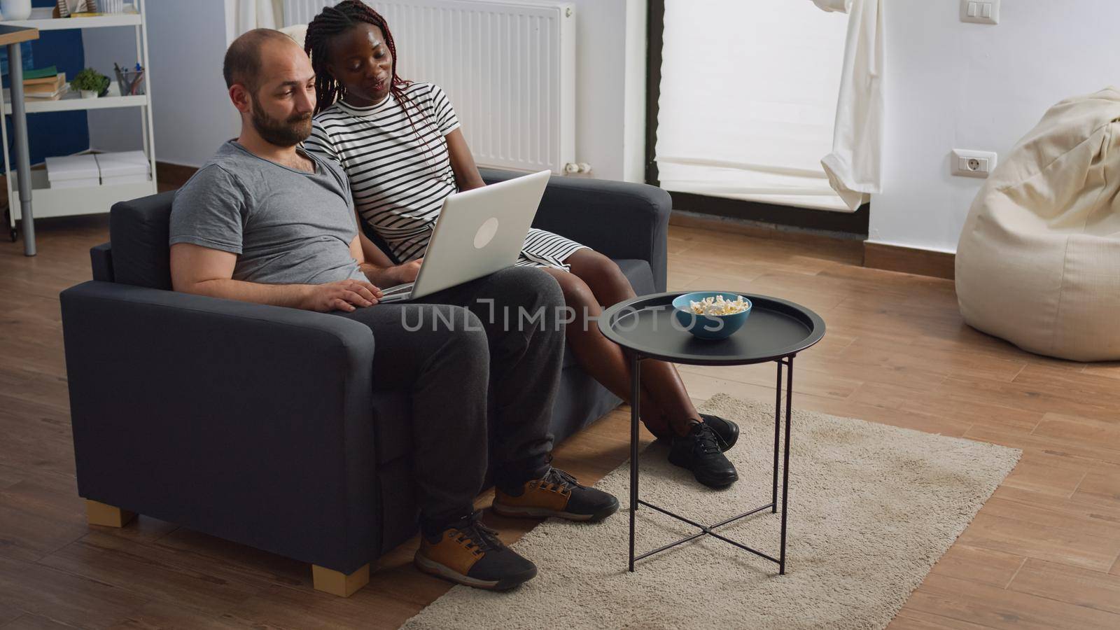 Modern interracial couple waving on video call conference by DCStudio
