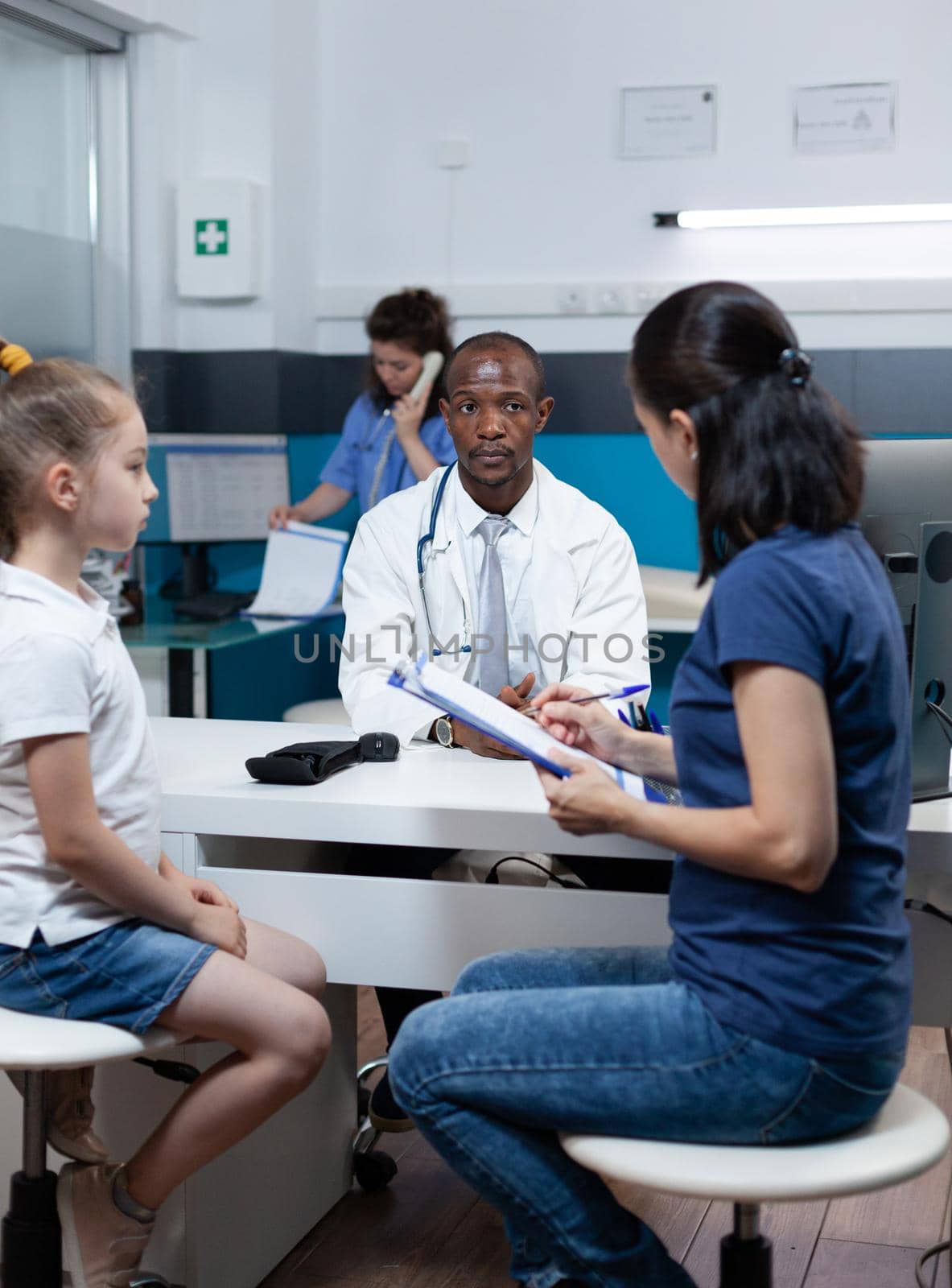 Patient mother writing medical accord on document while discussing sickness expertise by DCStudio