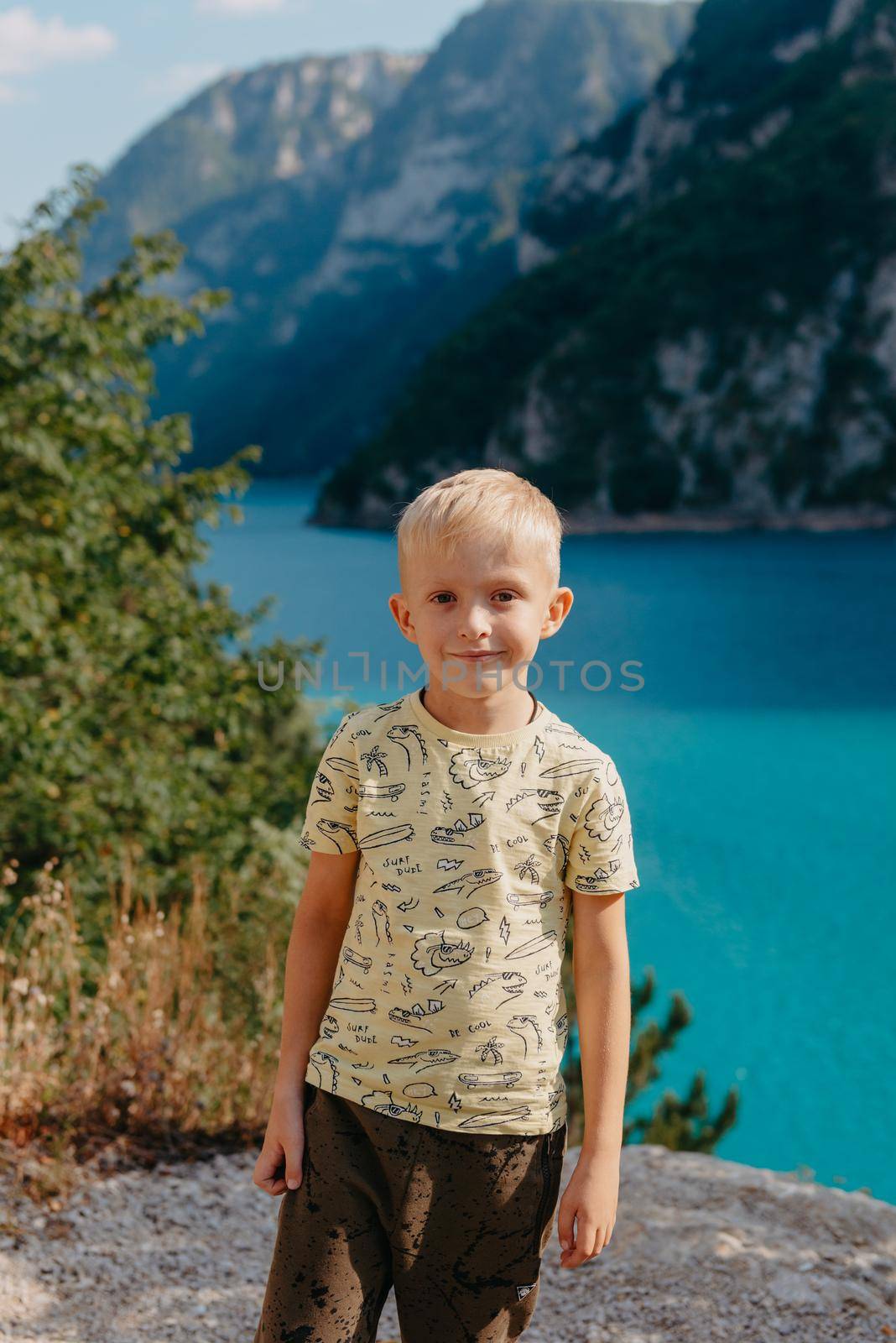 Boy young traveler on the background The famous Piva Canyon with its fantastic reservoir. View of road above Piva Lake (Pivsko Jezero) in Montenegro. Kid looks at river Piva, Montenegro. by Andrii_Ko