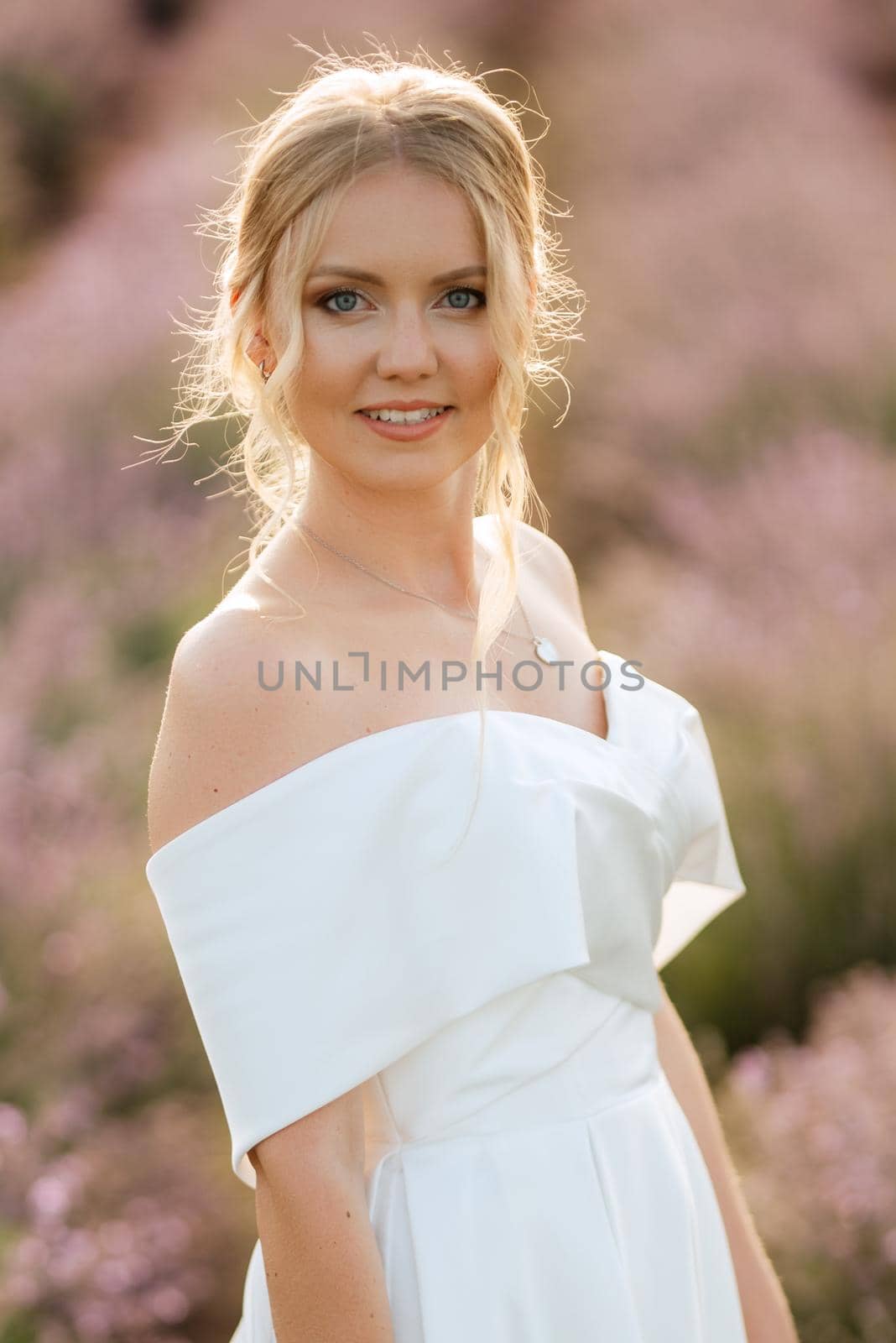 the bride in a white dress walks on the lavender field