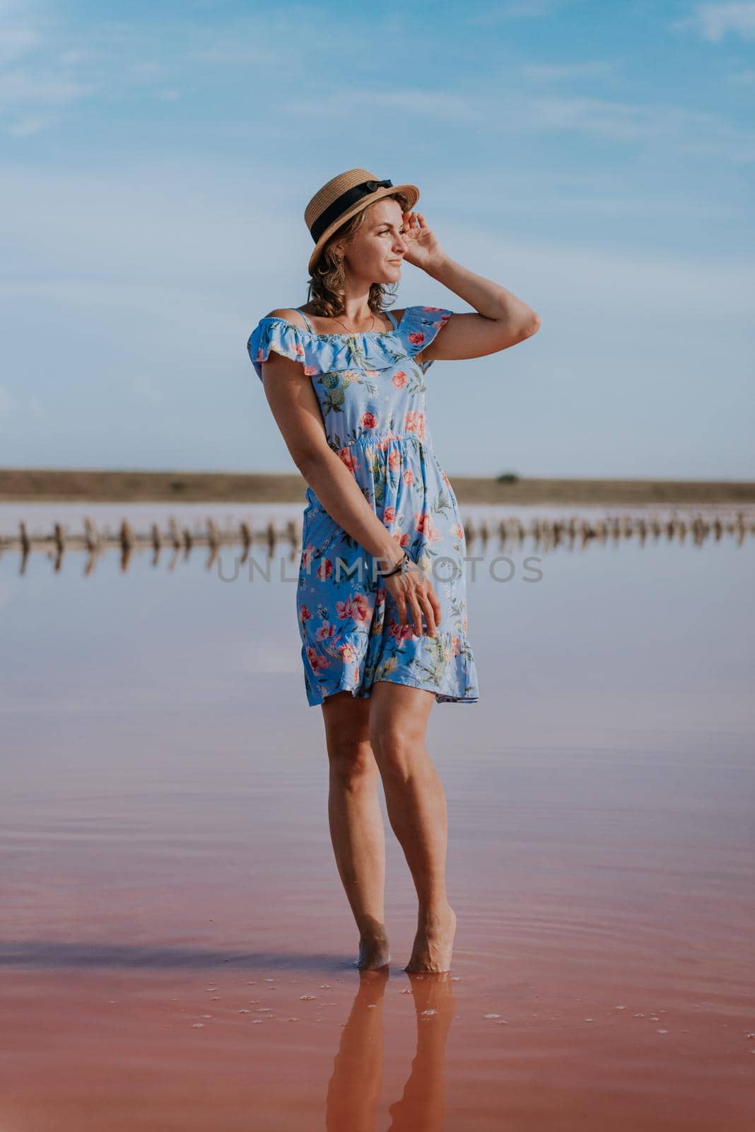 girl posing at sunset on the famous pink salt lake. reflection in the lake by Andrii_Ko