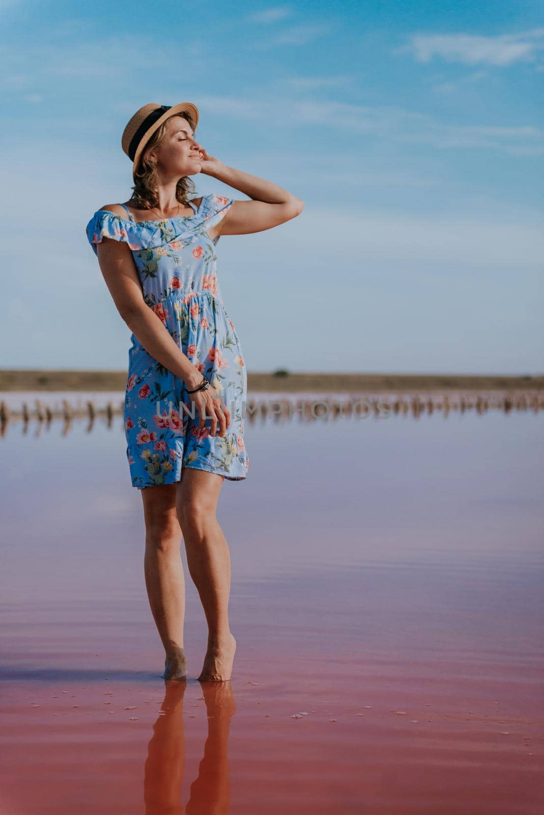 girl posing at sunset on the famous pink salt lake. reflection in the lake.