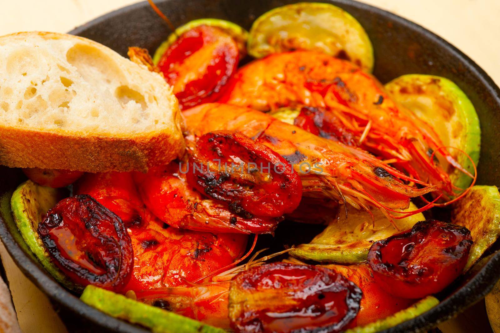 roasted shrimps on cast iron skillet  with zucchini and tomatoes