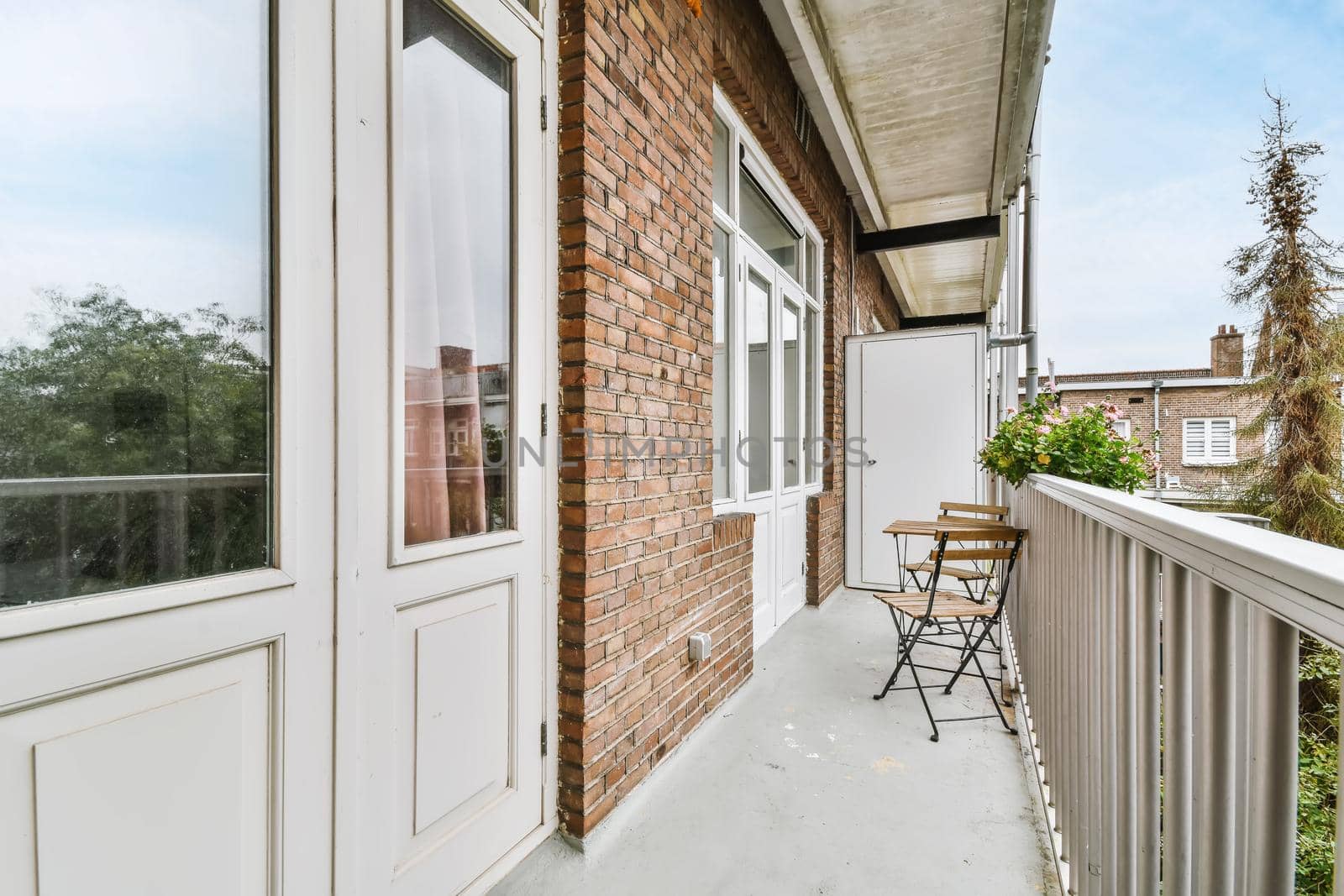 Elegant narrow and long balcony with wooden table and chairs