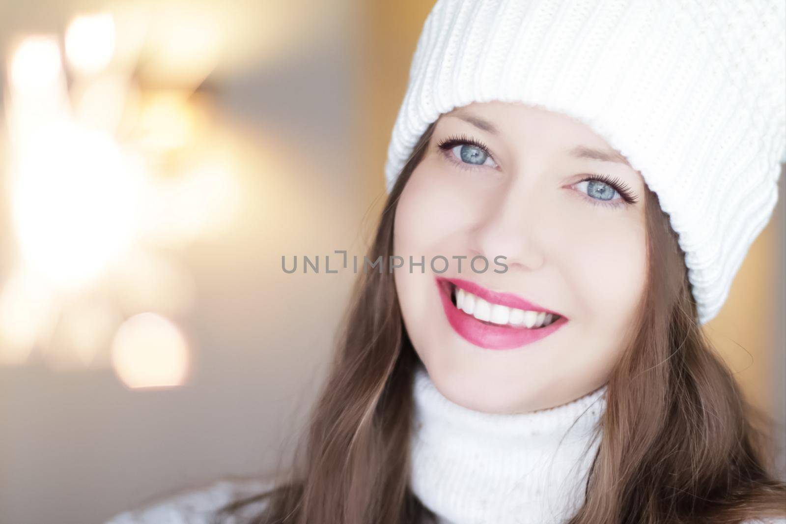 Christmas, people and winter holiday concept. Happy smiling woman wearing white knitted hat as closeup face xmas portrait.