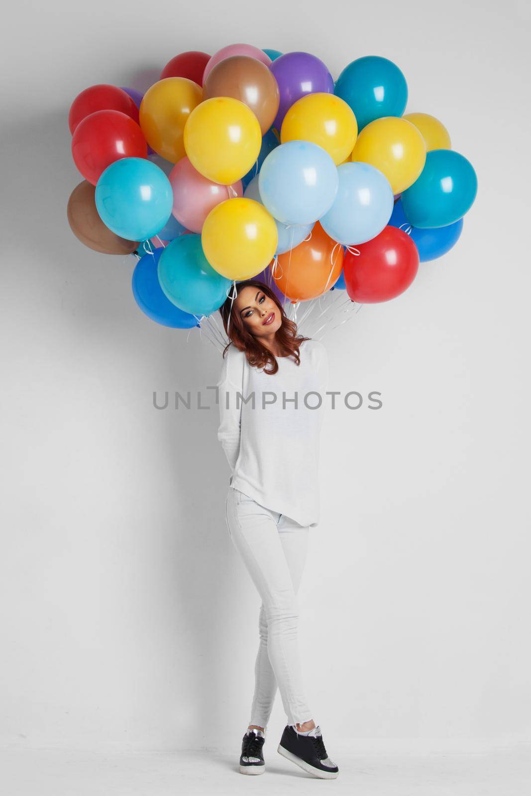 Full length of a happy woman holding balloons against white background